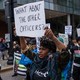 Protesters march. One holds a sign that reads, "What about the other officers?"