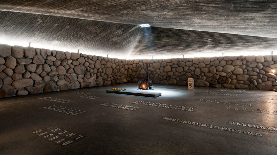 A gray floor inscribed with names surrounded by a stone wall with a pyramidal roof