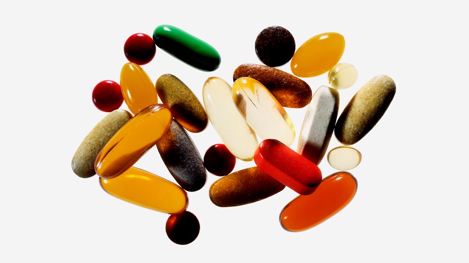 A jumble of pills and tablets in varying colors and opacities photographed on a white background