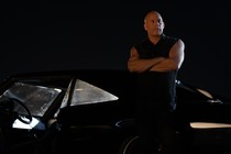 Vin Diesel stands with his arms crossed while leaning against a car, at night, in "Fast X"