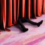 Legs are seen next to a red curtain