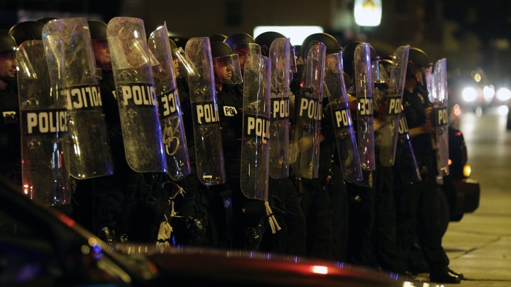 Police officers protected by clear shields move in single formation on a crowd during a protest Milwaukee on Sunday, August 14, 2016.