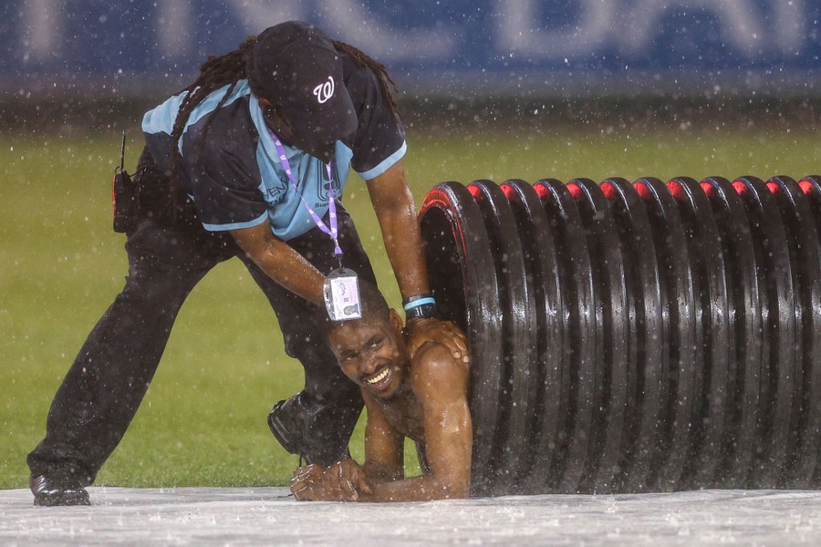 A man is removed from a large tube on a baseball field.