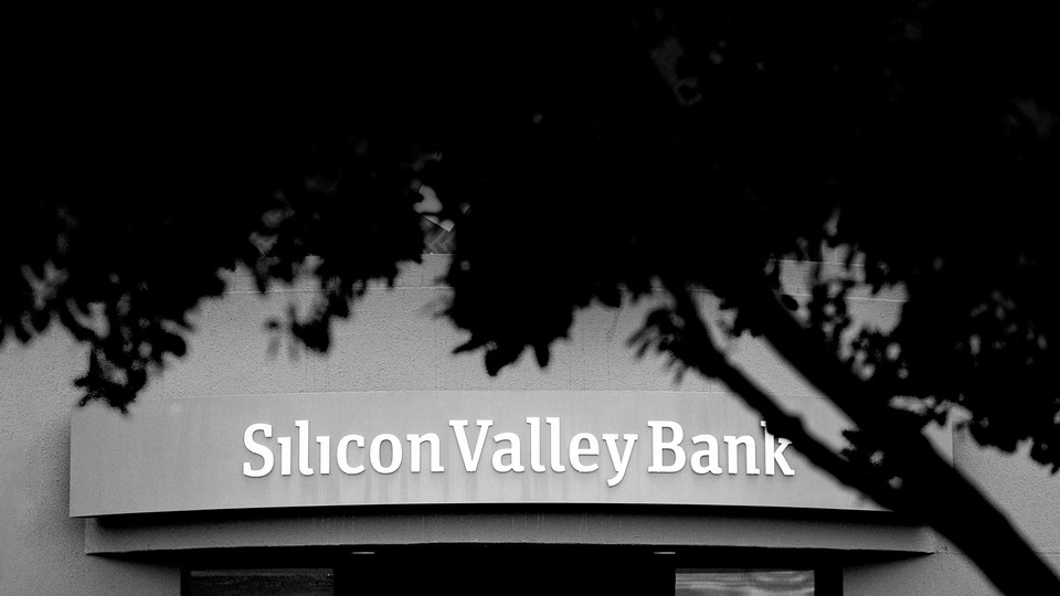 Black and white photo of Silicon Valley Bank branch partially covered by a tree.