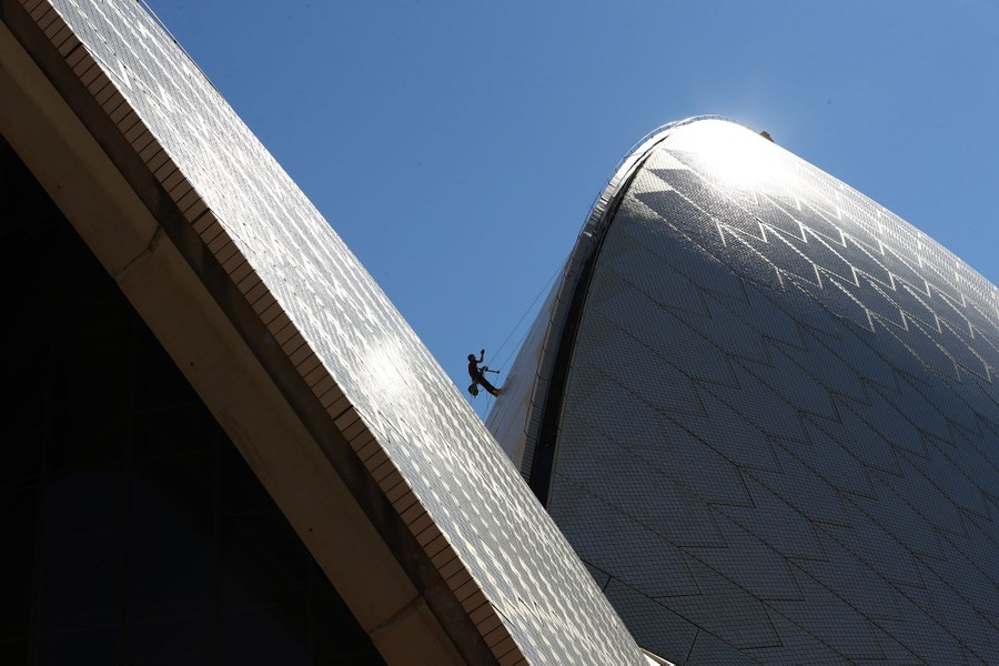 A maintenance worker climbs on the side of the Sydney Opera House.