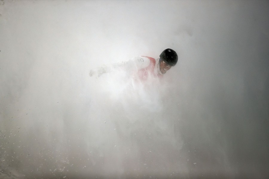 A crashing skier is barely visible amid a cloud of snow being thrown into the air.