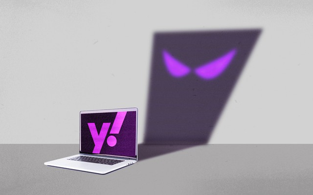 A laptop with a Yahoo logo on the screen, casting the shadow of a cartoon ghost