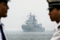 Two Chinese navy officers facing each other, a navy vessel at sea visible in the space between them.