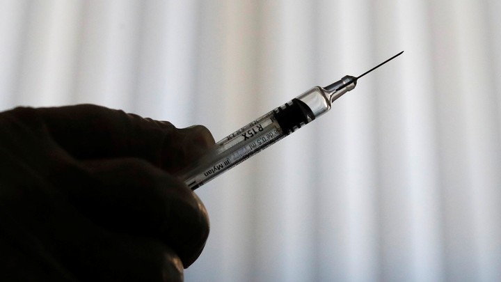 A shadowy hand holding a syringe