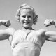 A black-and-white photo of a young woman in a sports bra showing off large biceps