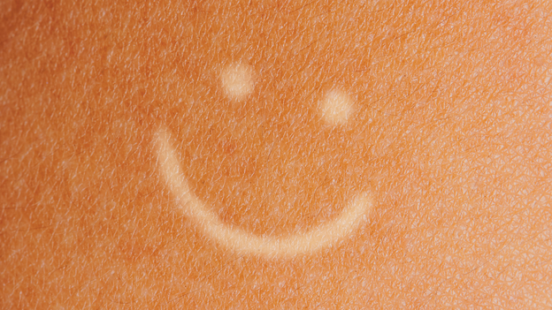 illustration of tanned skin with pale smiley face drawn on it