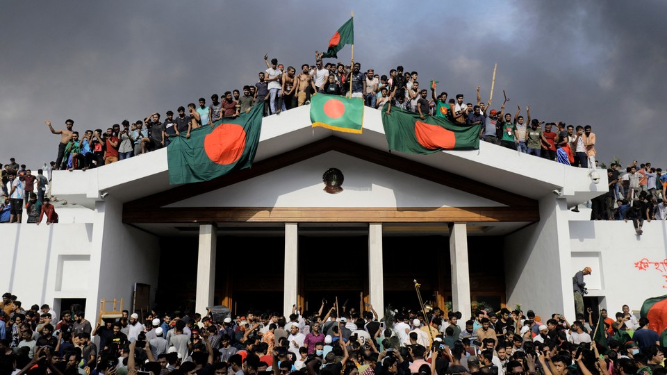 Anti-government protestors display Bangladesh’s national flag as they storm the prime minister’s palace.