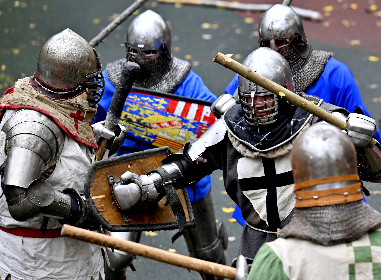 At least five people wearing armor stage a battle on a basketball court.