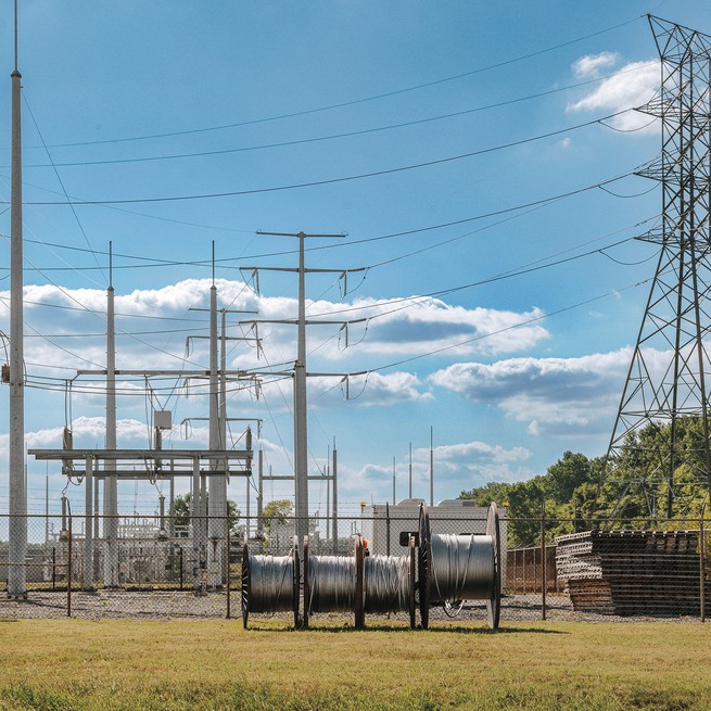 photo of transmission lines with large towers and large spools of metal cable in foreground