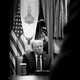 Black-and-white photo of President Trump in front of flags.