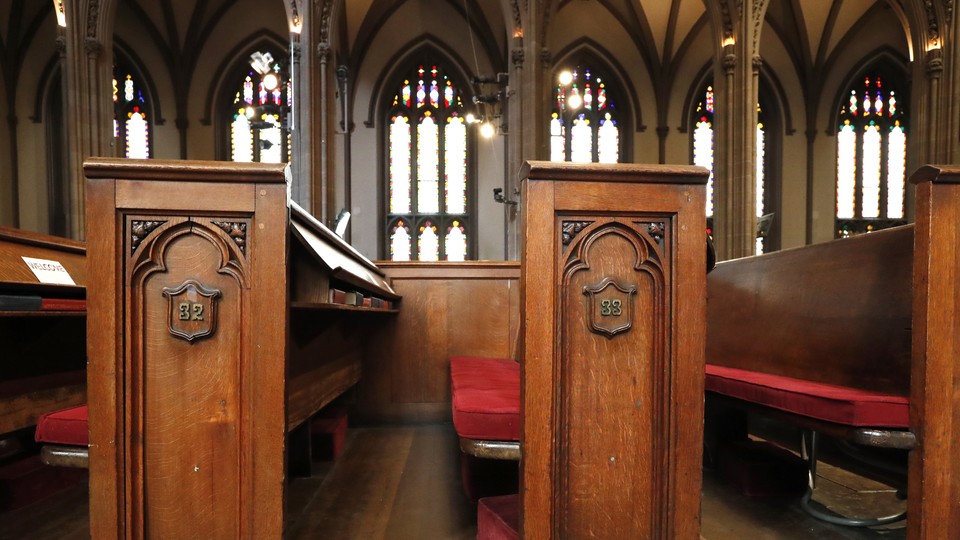 Empty church pews with stained glass in the background