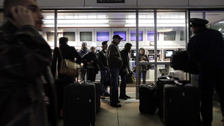 Travelers check their luggage at a United Airlines express check-in area at O'Hare International Airport in Chicago