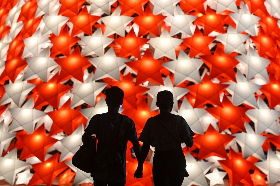 A couple is silhouetted by a brightly lit Christmas tree.