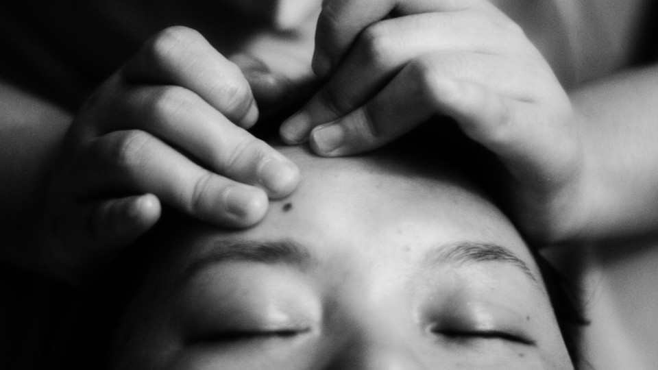 Someone's hands massage a person's forehead.