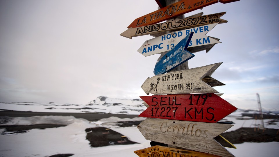 A signpost with the distances to various destinations against a snowy background