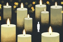 The silhouette of a woman stands small and alone among oversized lit candles