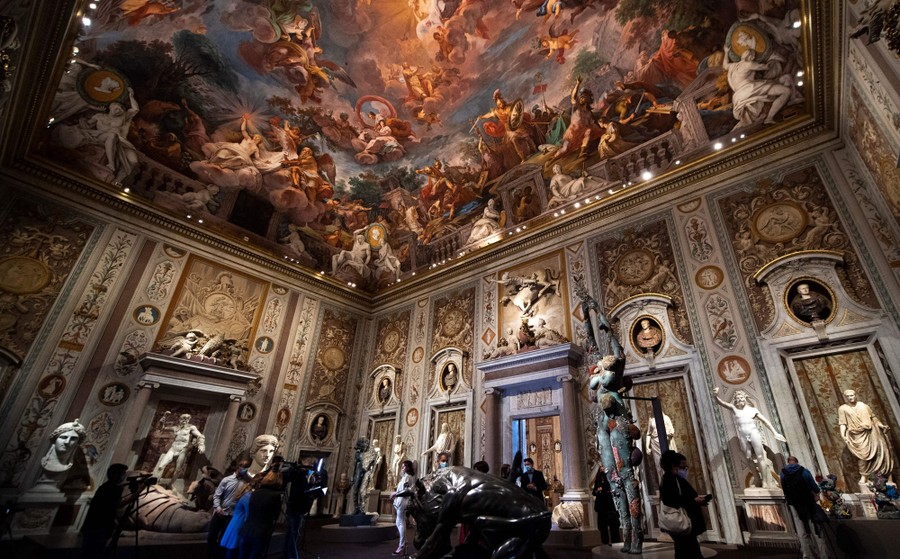 Sculptures stand inside an ornately decorated gallery room.