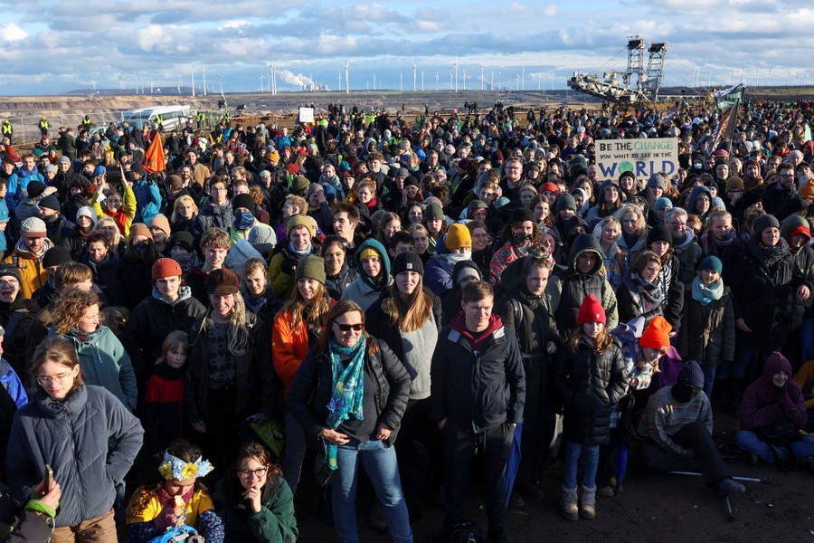 A large crowd of protesters stand near an open coal-mine pit.
