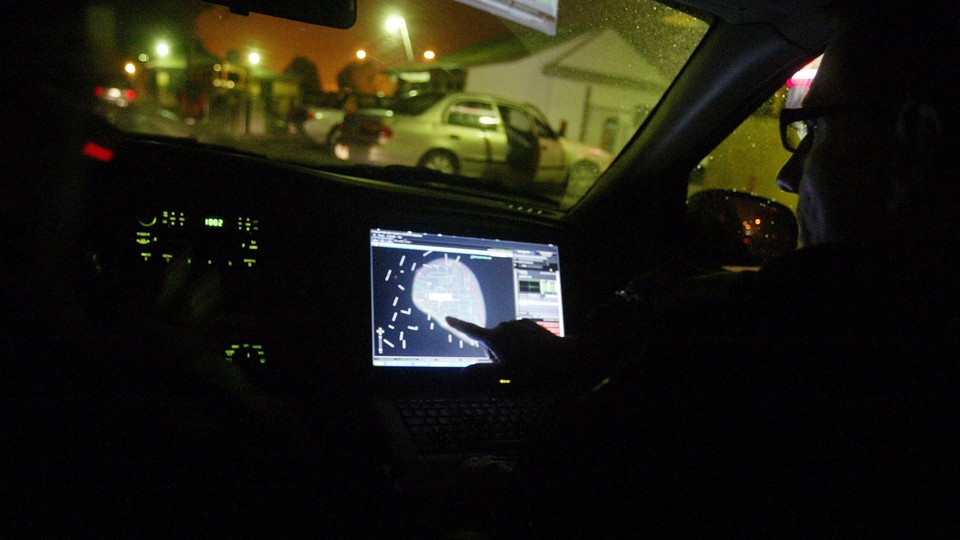 A person points at a GPS inside a vehicle on a residential street.