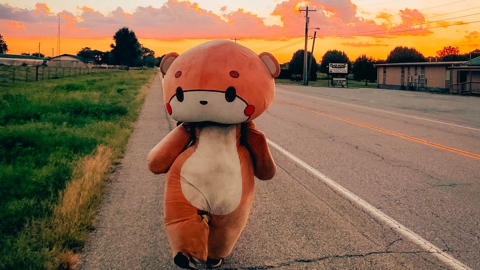 A man in a bear suit walking along a road