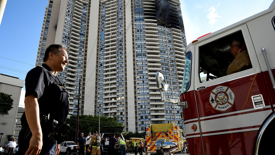 A police officer directs a fire truck at the Marco Polo apartment building after a fire broke out in it in Honolulu, Hawaii.