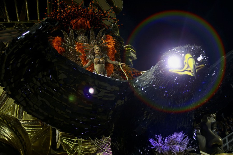 A dancer stands atop a large float depicting an eagle.