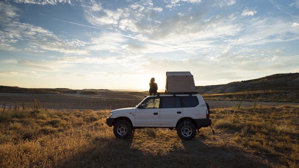 A woman standing by a car, looking out at a view