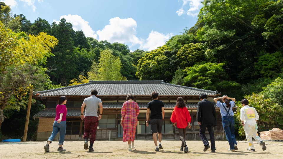 Eight adults walking toward a house in Japan