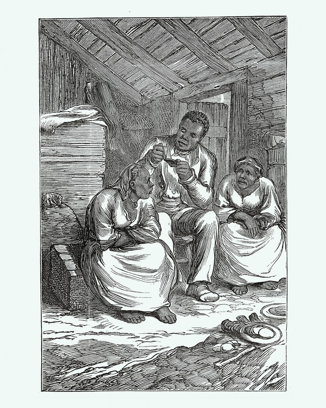 A man reads a Bible to two women in what looks like a barn.