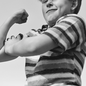 a young boy flexing a muscle in black and white