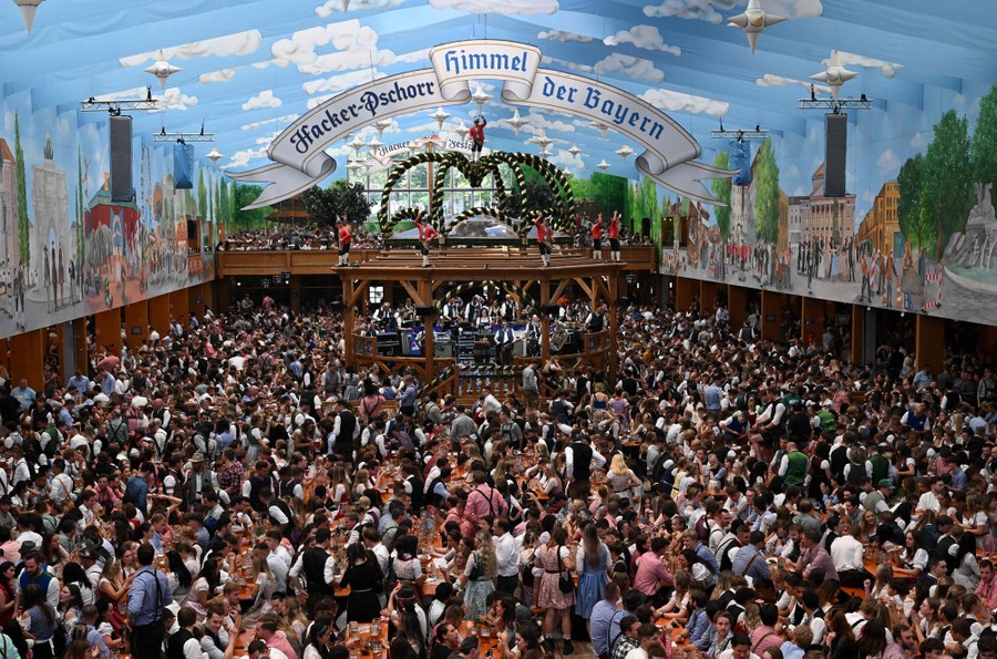 A large beer hall, full of people sitting at tables and walking in aisles