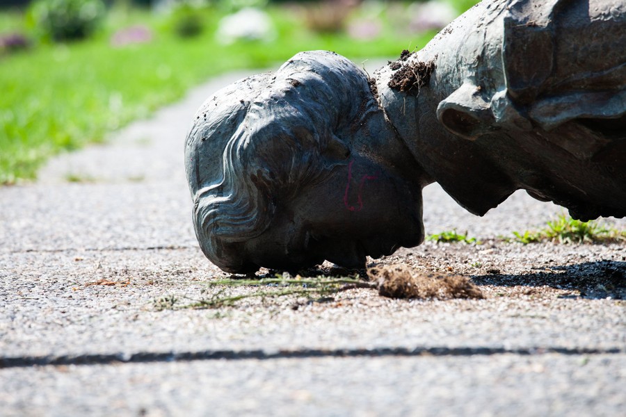 A statue of Queen Elizabeth lies facedown on the ground.