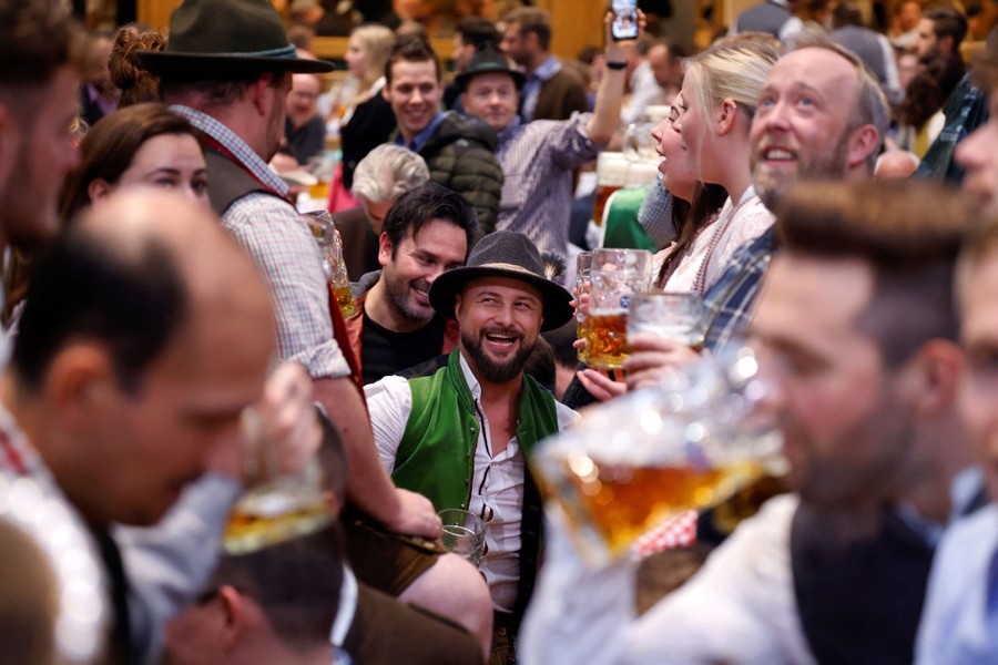 A crowd of people laugh and drink in a beer hall.