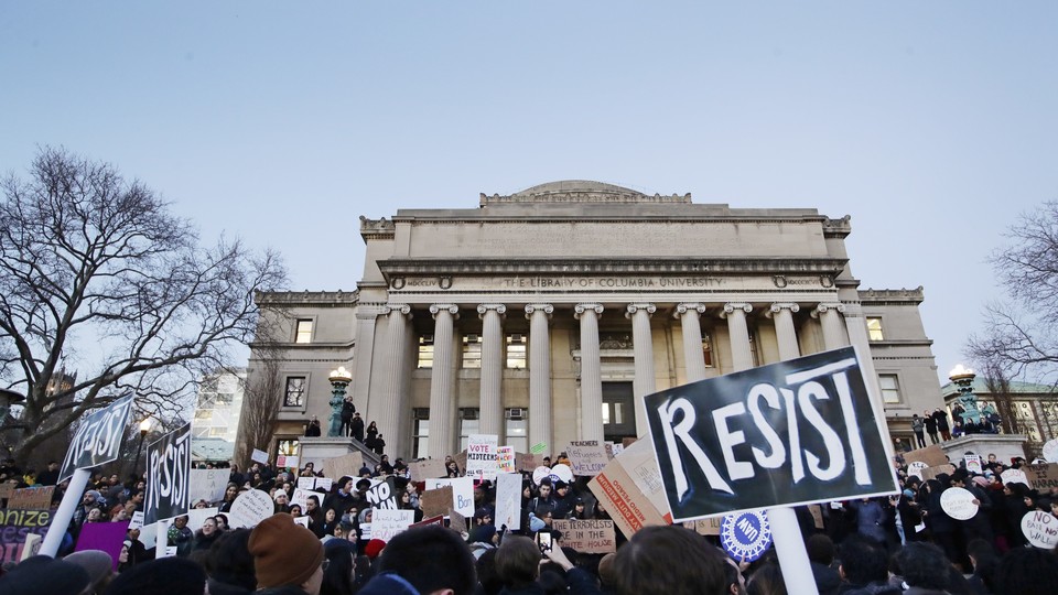 A group of students holds signs that read "resist" outside the Columbia University Library.