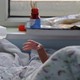 A baby stretches its hand from under a quilt in a hospital