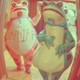 A stylized snapshot of two protesters dressed up in inflatable frog outfits, in a sepia-red hue