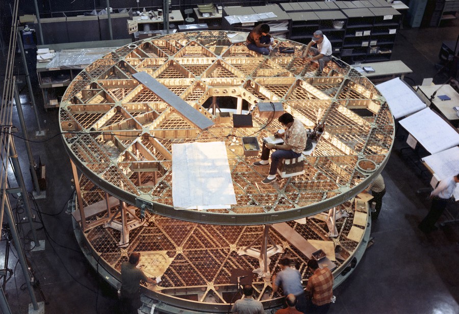 Inside a building, people work on two large circular platforms stacked on top of each other.