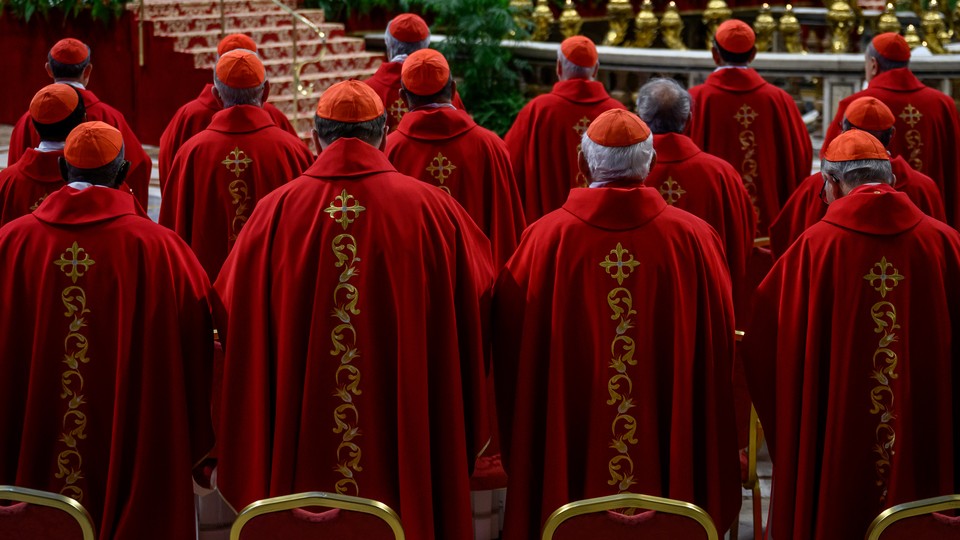 Three rows of cardinals facing away from the camera, wearing red robes and zucchettos