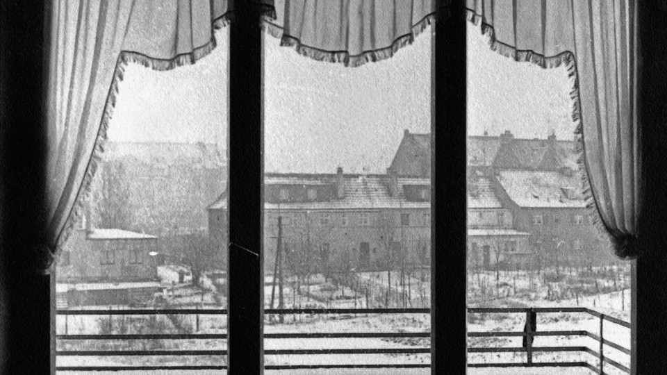 A snow scene looking out a window with ruffled curtains