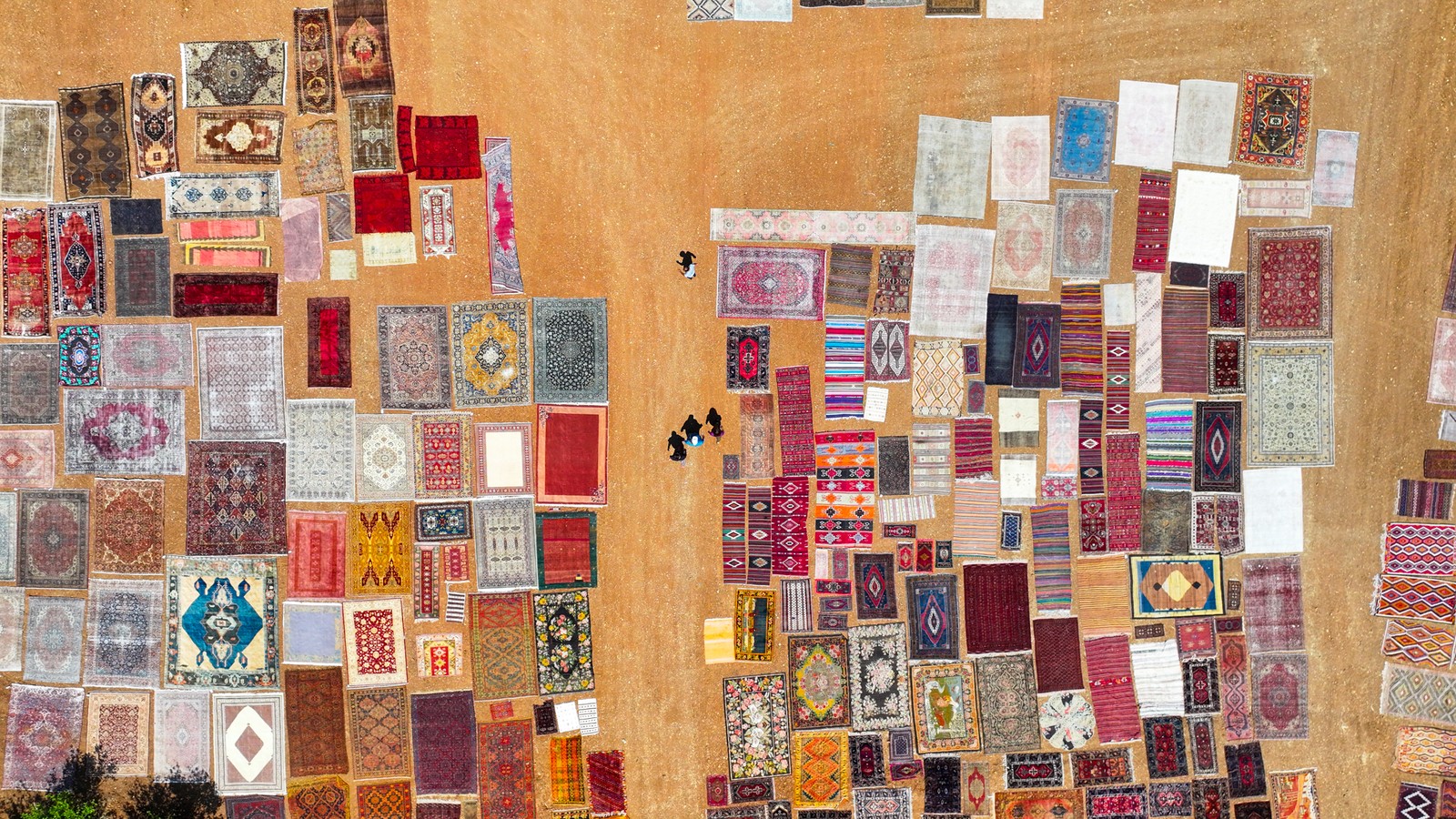 An aerial view of handwoven carpets laid out in an open field