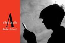 A black-and-white photograph shows a teenage boy looking at a smartphone.