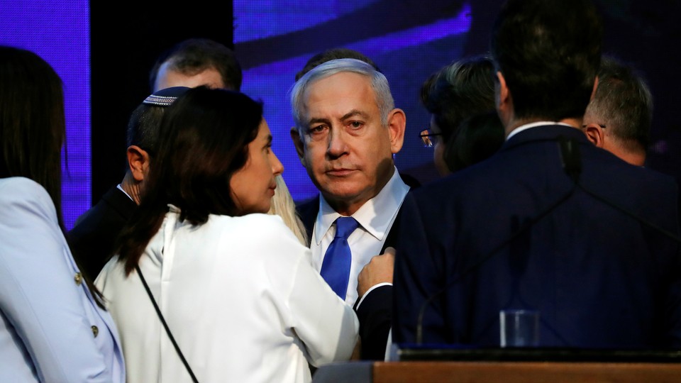 A despondent-looking Benjamin Netanyahu is surrounded by party colleagues.
