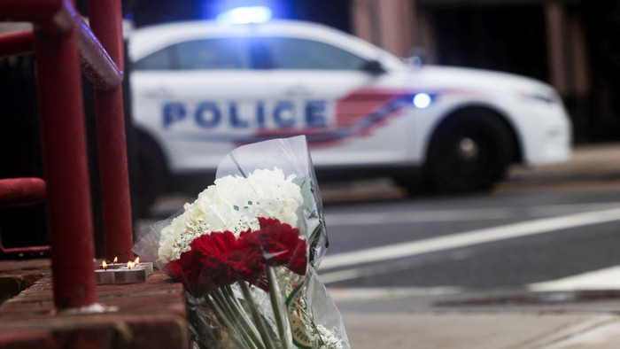 Flowers at a memorial in front of a police car