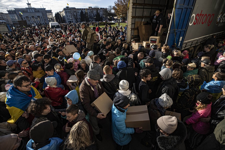 A crowd of people gather outside a truck where people are handing out aid.