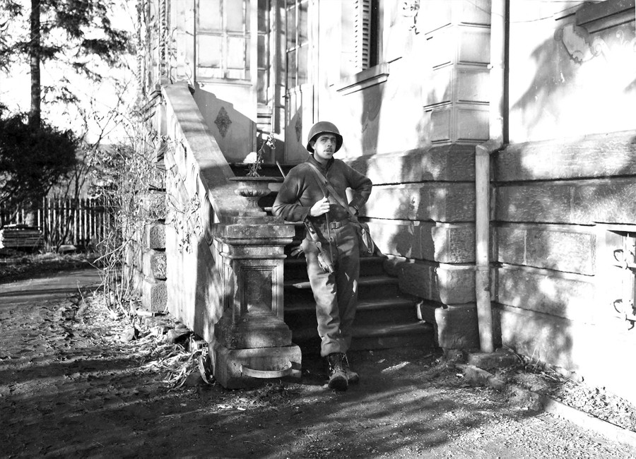 An American soldier stands guard outside a large house in France.